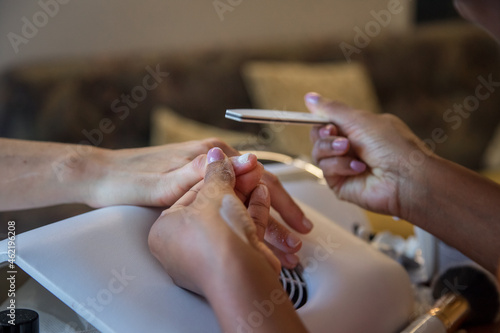Woman taking care of her nails with a manicure service. Hands of a person with a manicure. Process steps  polishing. 
