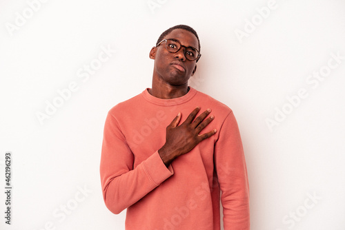 Young African American man isolated on white background taking an oath, putting hand on chest.