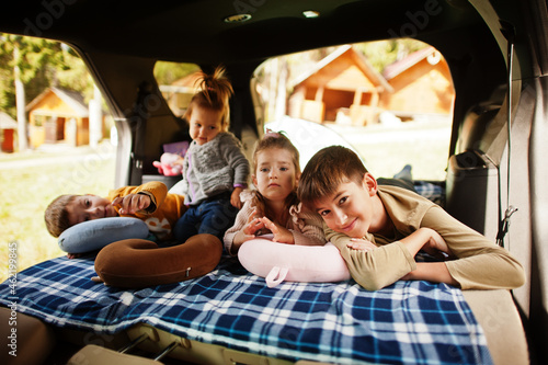 Family of four kids at vehicle interior. Children in trunk. Traveling by car, lying and having fun, atmosphere concept. © AS Photo Family