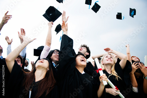 Group of diverse grads throwing caps up in the sky photo