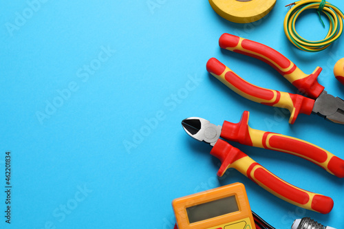 Flat lay composition with electrician's tools and accessories on light blue background, space for text