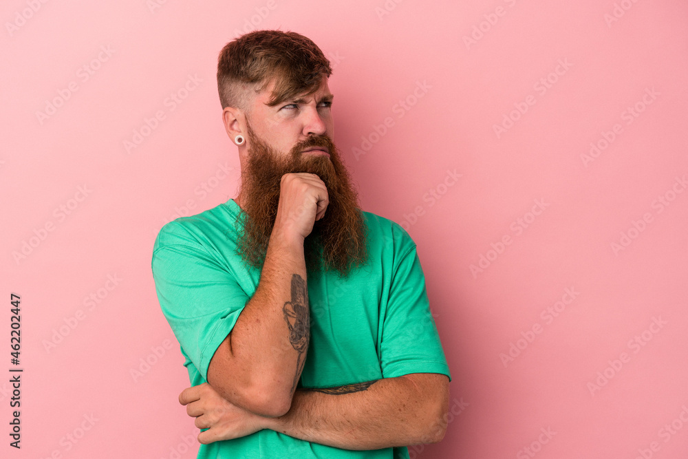 Young caucasian ginger man with long beard isolated on pink background thinking and looking up, being reflective, contemplating, having a fantasy. Young caucasian ginger man with long beard isolated on pink background thinking and looking up, being reflective, contemplating, having a fantasy.