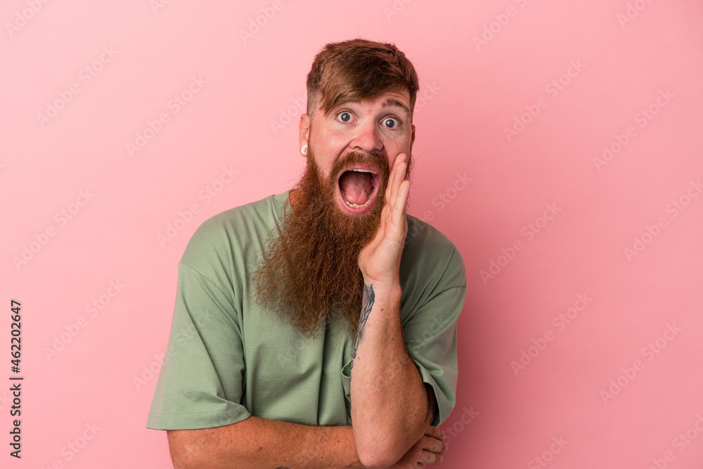 Young caucasian ginger man with long beard isolated on pink background shouts loud, keeps eyes opened and hands tense. Young caucasian ginger man with long beard isolated on pink background shouts loud, keeps eyes opened and hands tense.