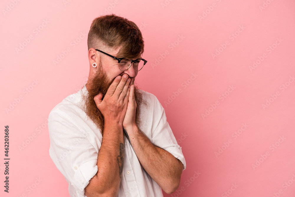 Young caucasian ginger man with long beard isolated on pink background laughing about something, covering mouth with hands. Young caucasian ginger man with long beard isolated on pink background laughing about something, covering mouth with hands.