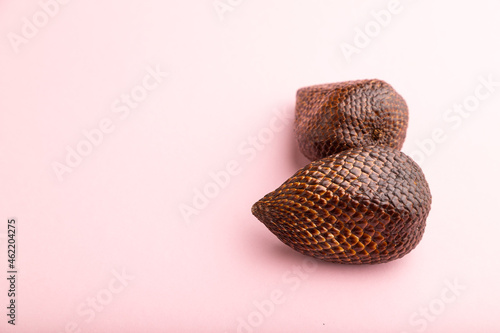 Salak or snake fruit on pink pastel background. Side view, copy space.