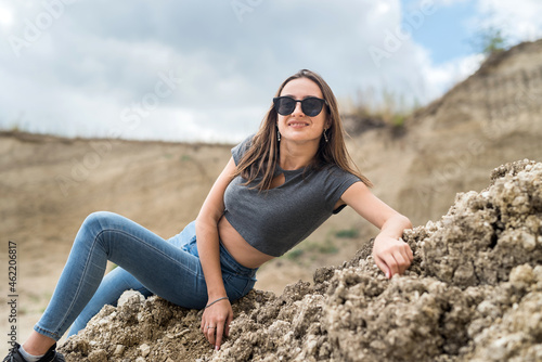 caucasian female model poses in sand quarry with blue sky, in summer sunny day