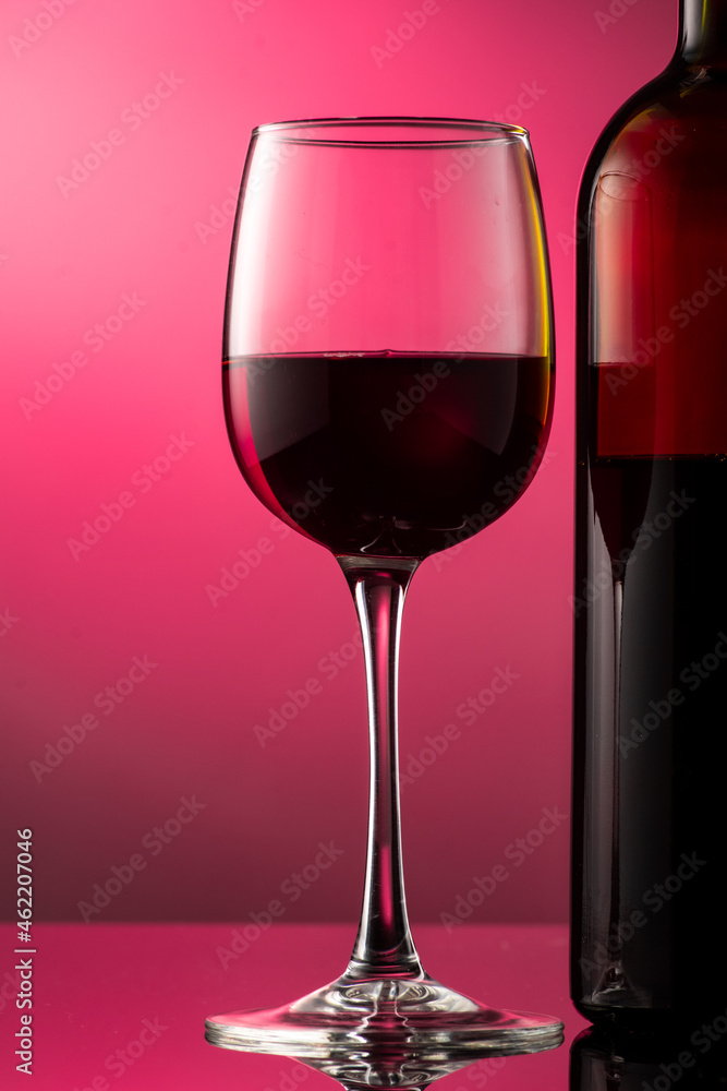 pouring red wine into glass with highlights on red background pouring red wine into glass with highlights on red background