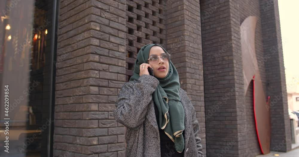 Muslim woman in veil talking by phone outdoors Muslim woman in veil talking by phone outdoors
