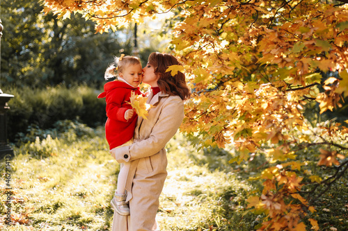 Autumn landscape. Happy mom and daughter, a child in a coat hugging together, walking and having fun in the fall forest on Mother's Day in nature outdoor. Selective focus
