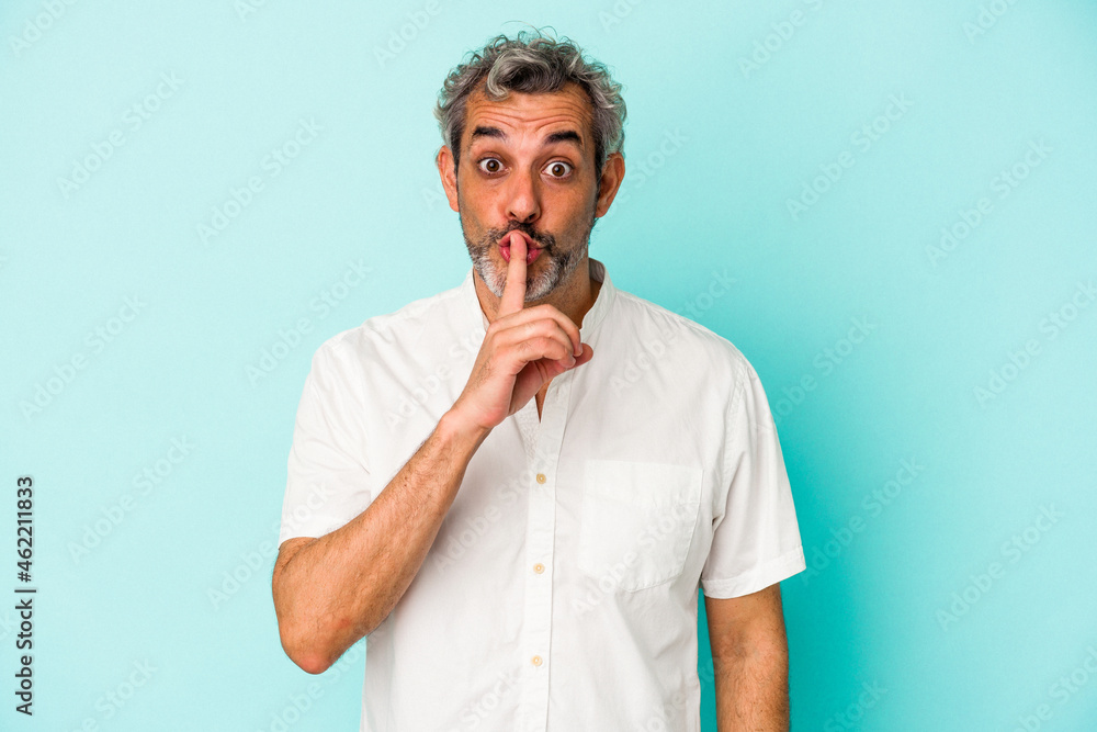 Middle age caucasian man isolated on blue background keeping a secret or asking for silence. Middle age caucasian man isolated on blue background keeping a secret or asking for silence.