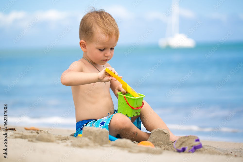 Cute baby boy playing with beach toys on tropical beach Cute baby boy playing with beach toys on tropical beach
