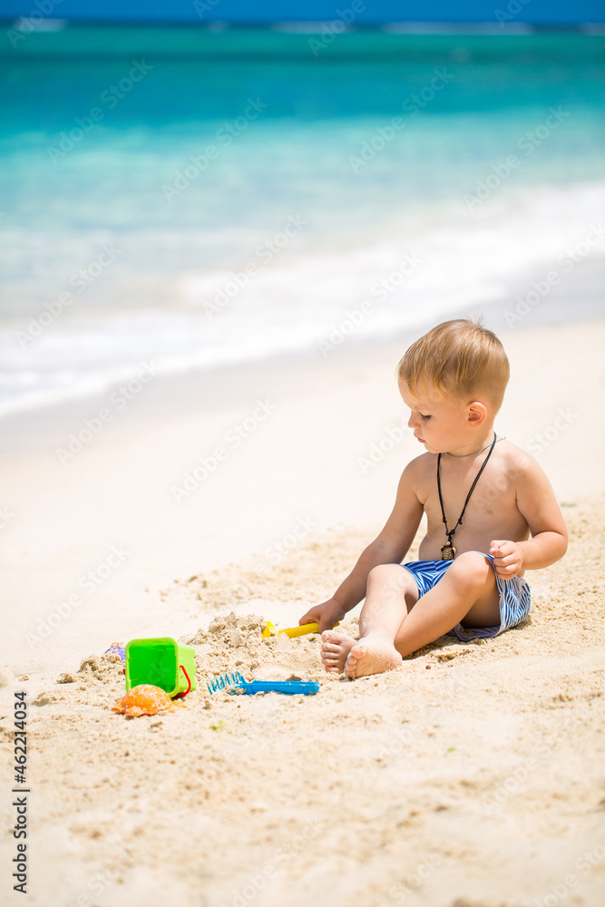 Cute baby boy playing with beach toys on tropical beach Cute baby boy playing with beach toys on tropical beach