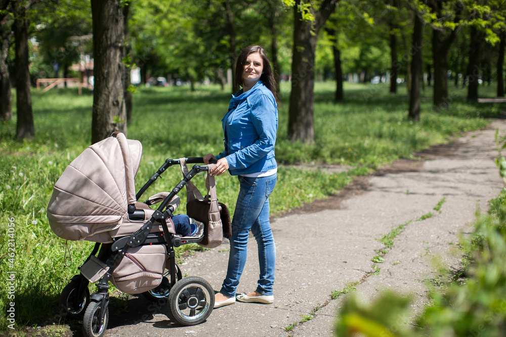 Young mother walking and pushing a stroller in the park Young mother walking and pushing a stroller in the park