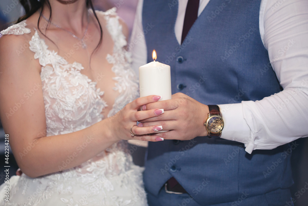 Wedding ceremony, paraphernalia, the bride and groom hold a large candle in their hand Wedding ceremony, paraphernalia, the bride and groom hold a large candle in their hand