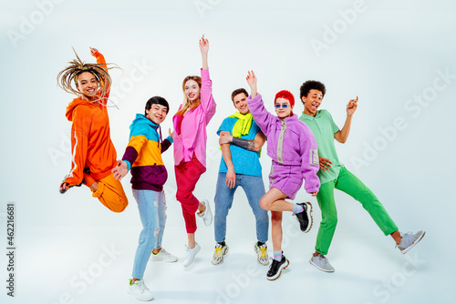 Smiling young male and female friends dancing against white background
