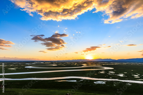 Bayinbuluke Grassland and winding river natural scenery in Xinjiang at sunset,China.The winding river is on the green grassland. photo