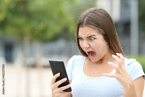 Obraz na plátně Angry teen watching media on smartphone