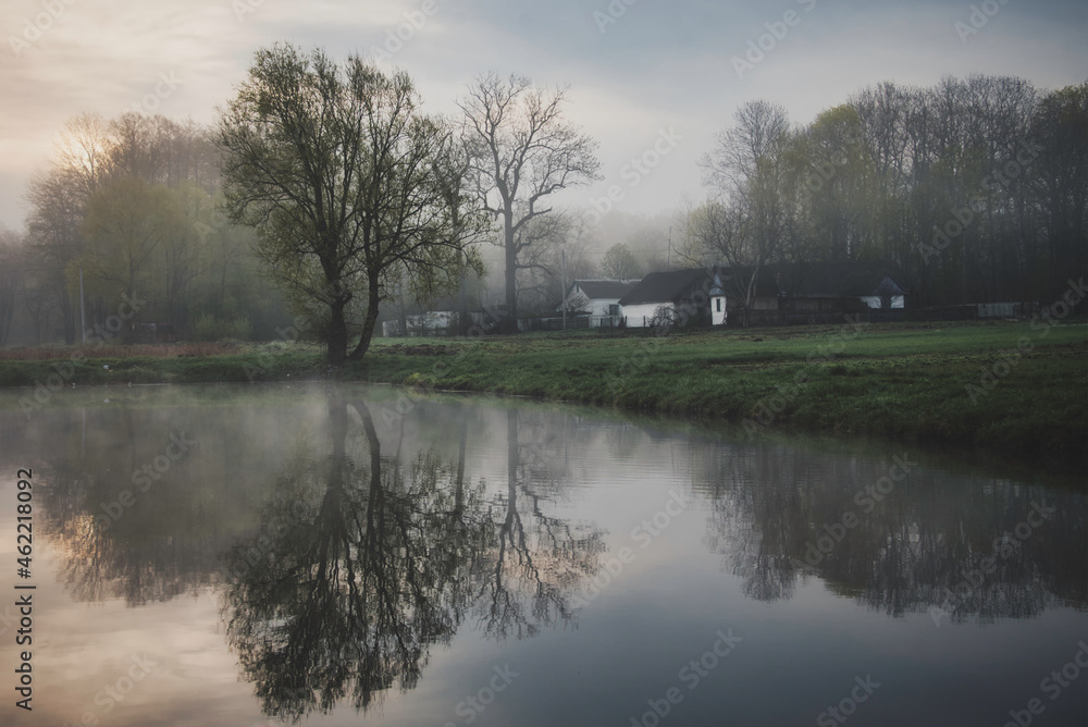 Early foggy morning at the pond. Reflection of trees in the water. Spring morning. Early foggy morning at the pond. Reflection of trees in the water. Spring morning.