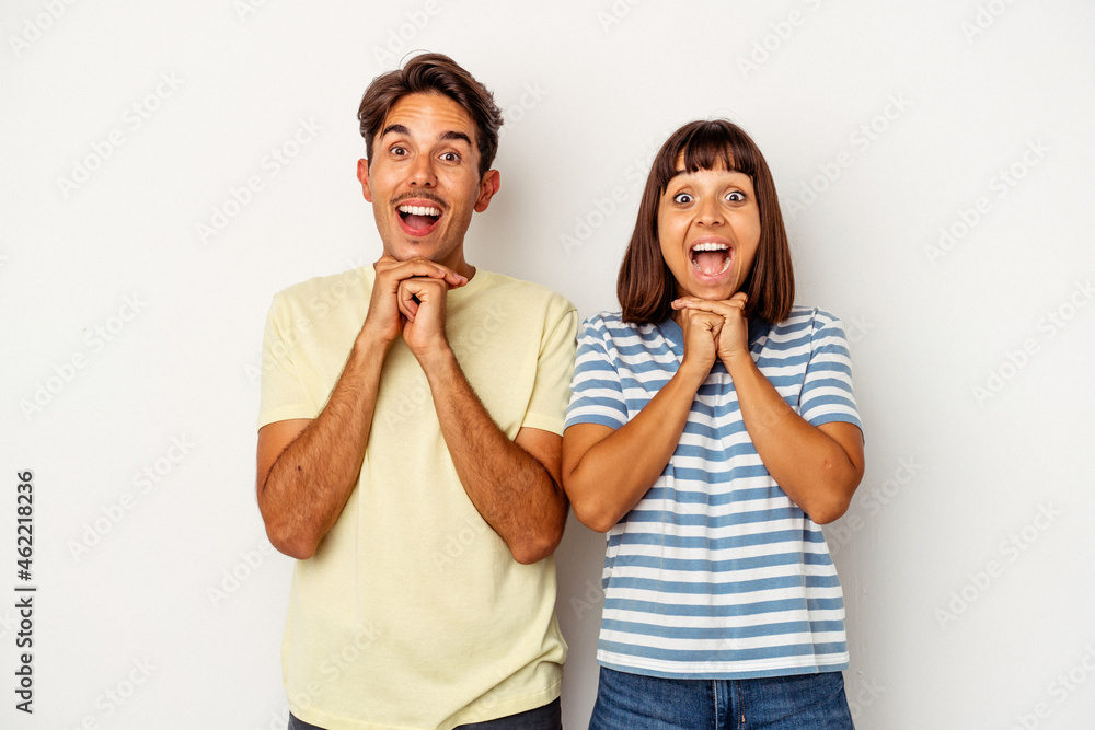 Young mixed race couple isolated on white background praying for luck, amazed and opening mouth looking to front. Young mixed race couple isolated on white background praying for luck, amazed and opening mouth looking to front.