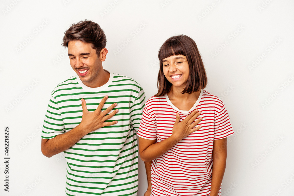 Young mixed race couple isolated on white background laughing keeping hands on heart, concept of happiness. Young mixed race couple isolated on white background laughing keeping hands on heart, concept of happiness.
