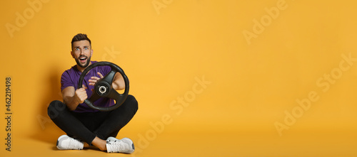 Tableau sur toile Emotional man with steering wheel on yellow background