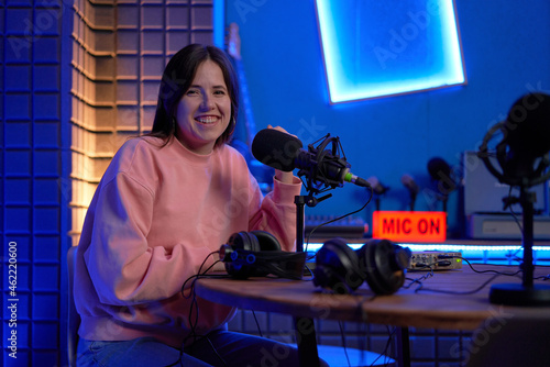 Happy woman smiling at camera while recording podcast in studio photo