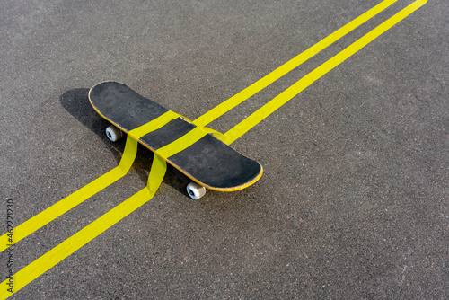 Yellow adhesive tapes over skateboard on road during sunny day