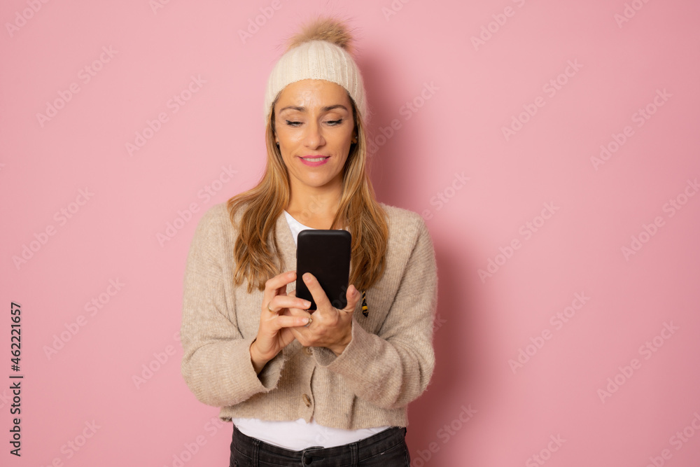 Young woman in winter clothing talking on mobile phone isolated over pink background. Young woman in winter clothing talking on mobile phone isolated over pink background.