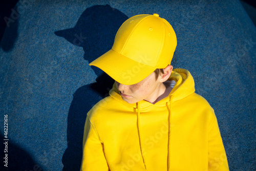 Boy wearing yellow cap and sweatshirt at skateboard park
