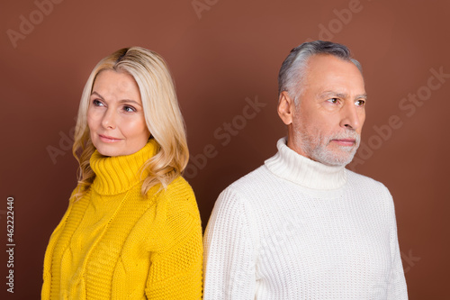 Portrait of two attractive minded middle-aged people overthinking wearing warm jumper isolated over brown color background