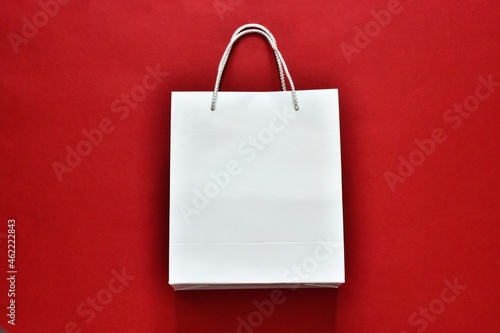 Black Friday sale. Black Friday sale shopping. White paper shopping bag on a red background. Flat lay, copy space. Advertising