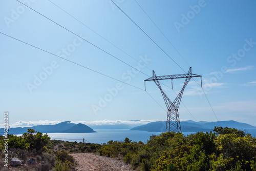 Panoramic landscape of Lefkada island coast in Greece with green woods, blue sky and electrical support line. Summer travel