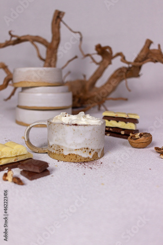 A cup of cocoa with cream and chocolate on a light background