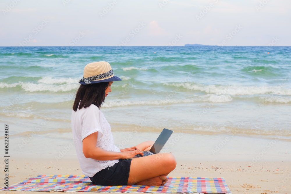 Young asian woman playing laptop computer on tropical beach