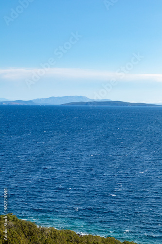 Greek islands sea shore on a bright clear blue day. Stormy rippled water and blue sky. Lefkada island, Ionian sea coast, Greece. Vertical © Kathrine Andi