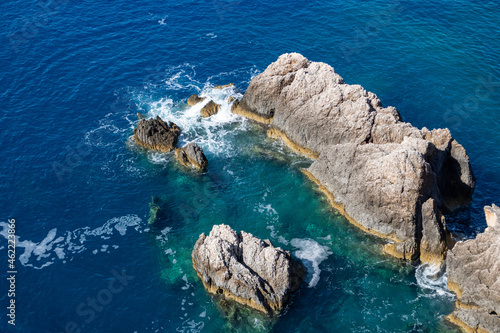 Calm waves splash on rocks in blue Ionian sea. Summer nature in Lefkada island, Greece. Top aerial view