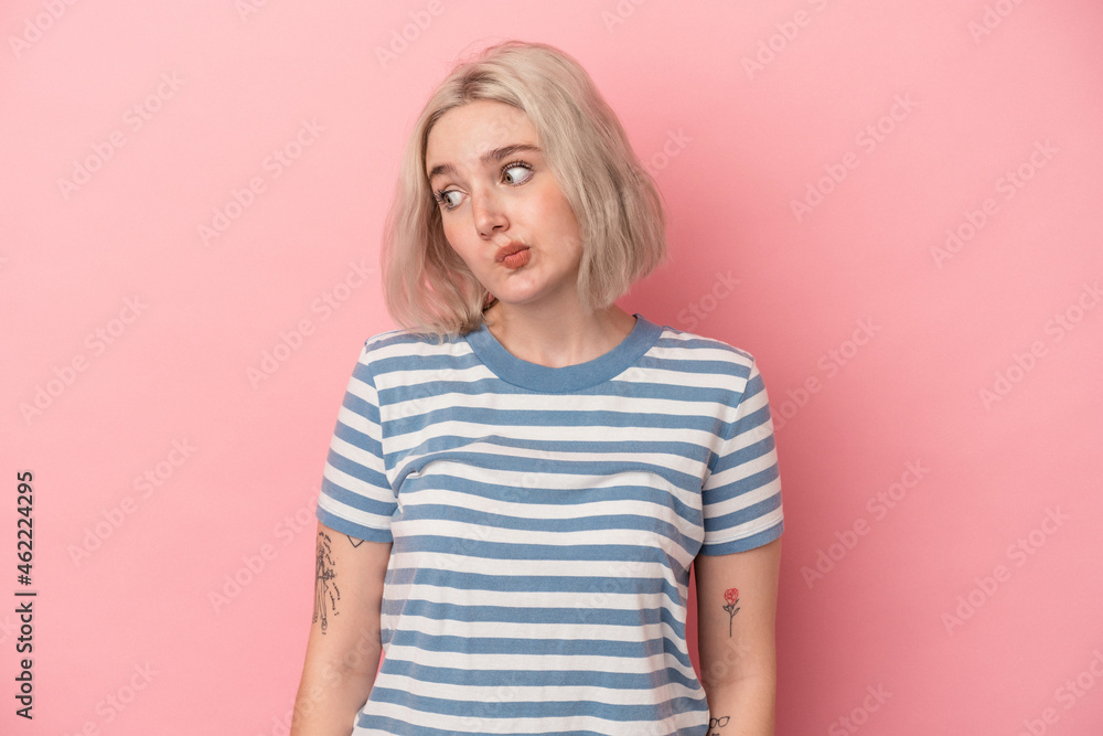 Young caucasian woman isolated on pink background shrugs shoulders and open eyes confused. Young caucasian woman isolated on pink background shrugs shoulders and open eyes confused.