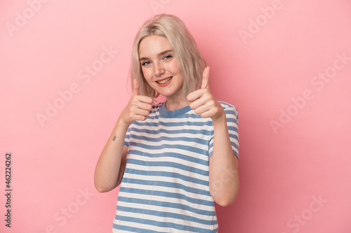 Young caucasian woman isolated on pink background raising both thumbs up, smiling and confident.