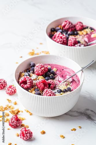 Berry smoothie bowl with granola, coconut and hemp seeds, marble background. Vegan food concept.