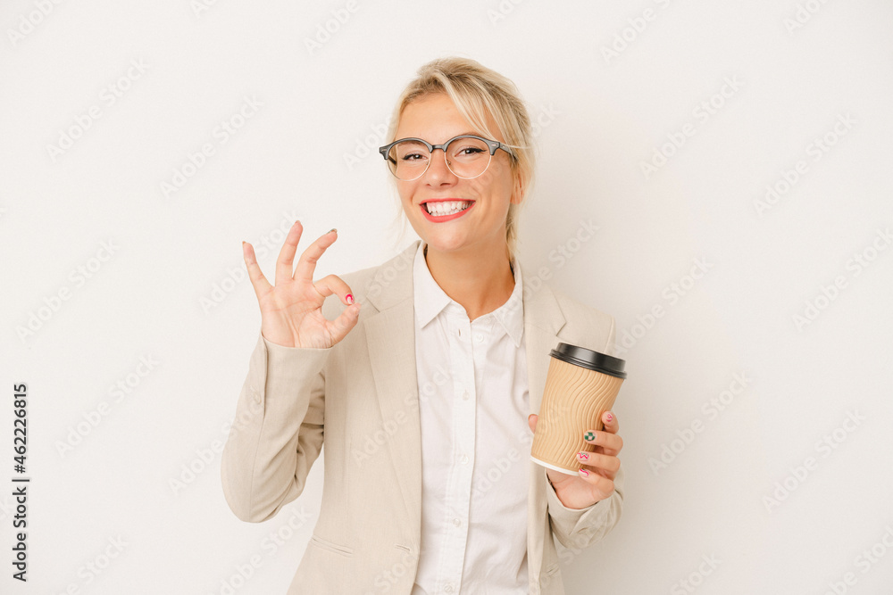 Young business Russian woman holding take away coffee isolated on white background cheerful and confident showing ok gesture. Young business Russian woman holding take away coffee isolated on white background cheerful and confident showing ok gesture.