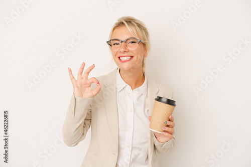 Young business Russian woman holding take away coffee isolated on white background cheerful and confident showing ok gesture.