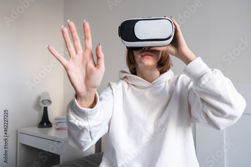 The girl looks into virtual reality glasses at home. A young woman plays virtual games through a special device.