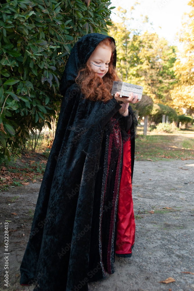 girl for Halloween in a black cloak with space for text girl for Halloween in a black cloak with space for text