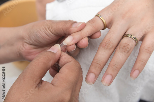Bild auf Leinwand A manicurist places a clear nail extension to the finger