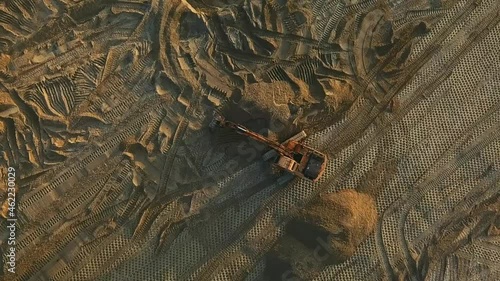 Excavator evens sand surface at construction site during sunset