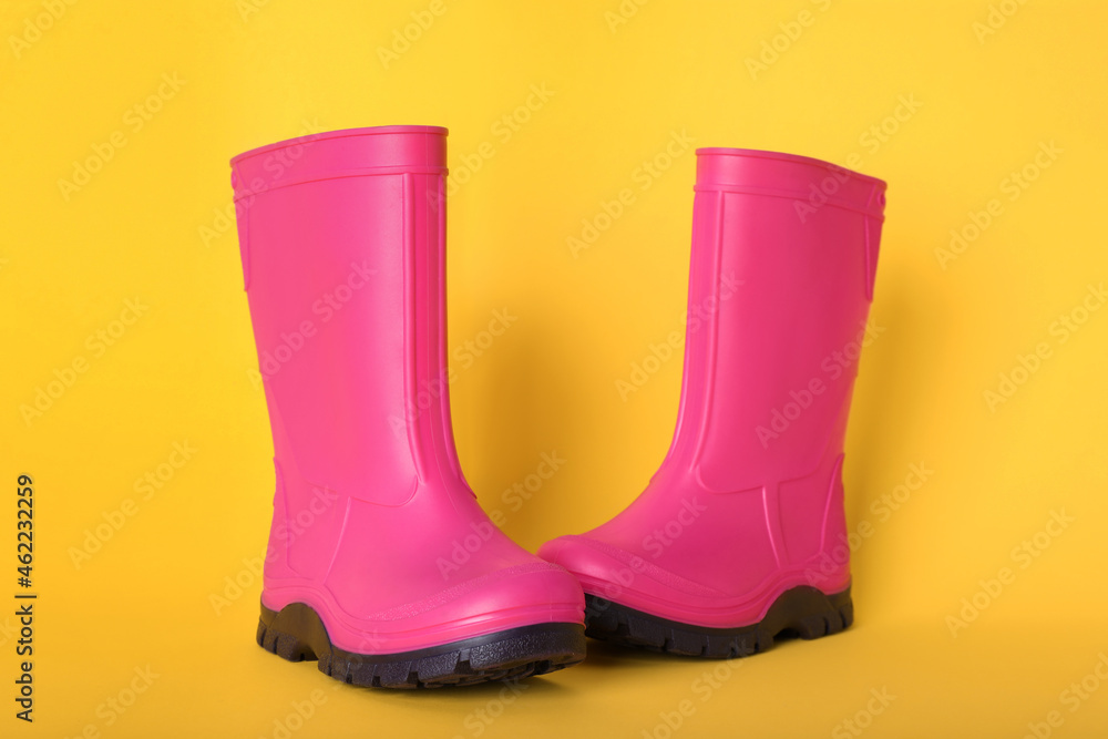 Pair of bright pink rubber boots on pale orange background Pair of bright pink rubber boots on pale orange background
