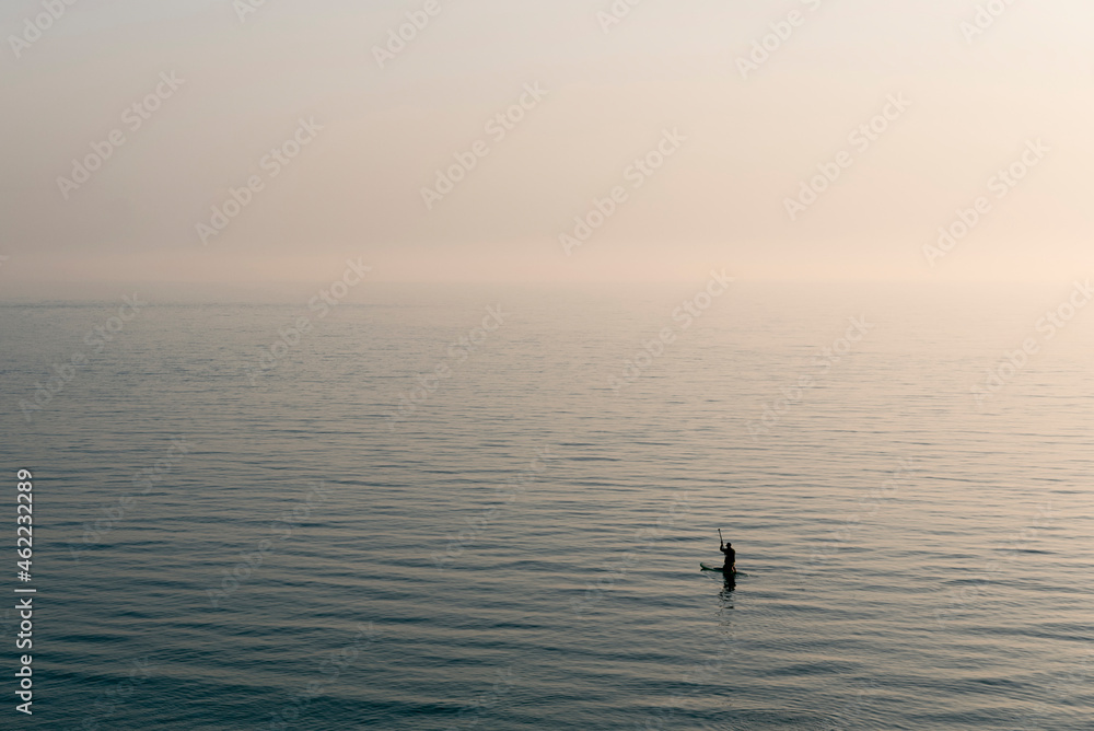 Silhouette of a man paddle boarding on the sea