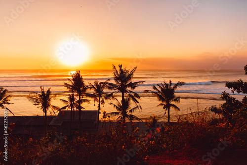 Panorama of sunset or sunrise with big ocean waves and silhouette of palms