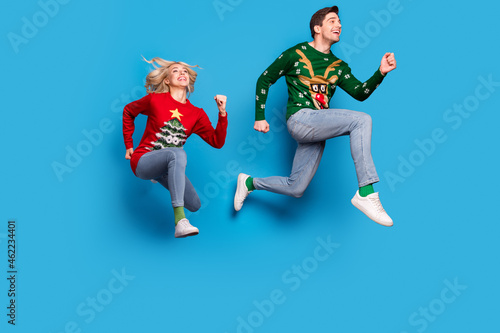Full length body size photo couple jumping up running fast in sweaters isolated pastel blue color background