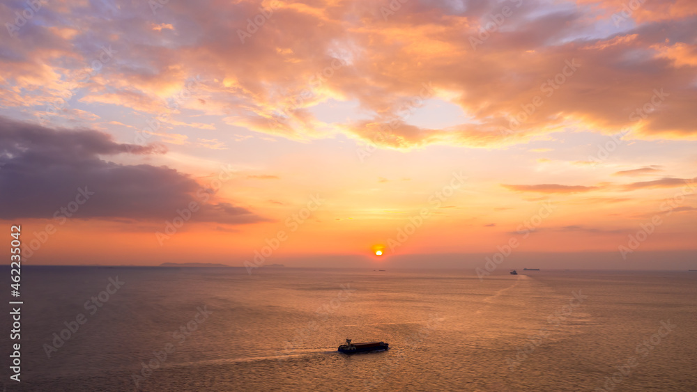 Photograph Of Seascape Aerial View at Twilight And Small Container Ship Sailing In Sea Pink Sky And The Sunset Background. Photograph Of Seascape Aerial View at Twilight And Small Container Ship Sailing In Sea Pink Sky And The Sunset Background.